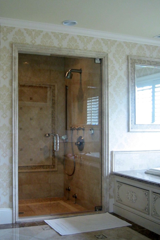 Inspiration for a large traditional master bathroom in Boston with recessed-panel cabinets, beige cabinets, a drop-in tub, a double shower, a one-piece toilet, beige tile, limestone, beige walls, limestone floors, an undermount sink, marble benchtops, beige floor and a hinged shower door.