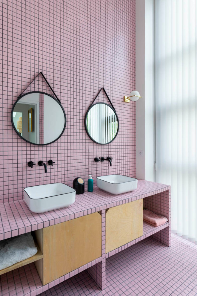 На фото: большая главная ванная комната с плоскими фасадами, светлыми деревянными фасадами, отдельно стоящей ванной, инсталляцией, розовой плиткой, керамической плиткой, розовыми стенами, полом из керамической плитки, настольной раковиной, столешницей из плитки, розовым полом, открытым душем, розовой столешницей, окном, тумбой под две раковины и напольной тумбой