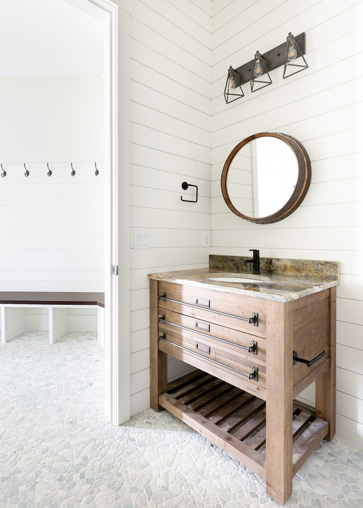 This is an example of a mid-sized country 3/4 bathroom in Minneapolis with medium wood cabinets, pebble tile floors, granite benchtops, multi-coloured benchtops, white walls, shaker cabinets, a two-piece toilet, an undermount sink and grey floor.