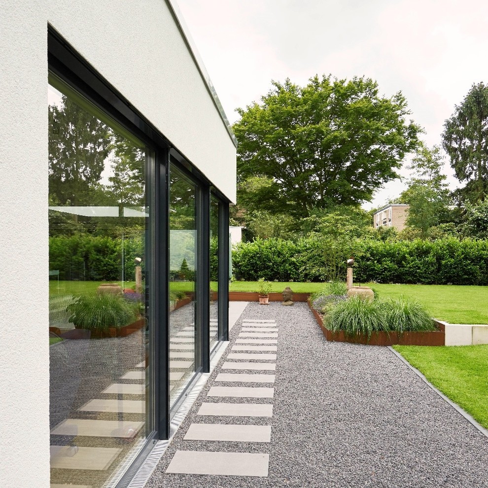 Design ideas for a large contemporary side yard garden for summer in Dusseldorf with a retaining wall and gravel.