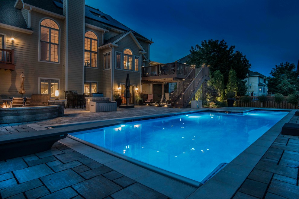 Inspiration for a mid-sized traditional backyard l-shaped lap pool in Chicago with concrete pavers.