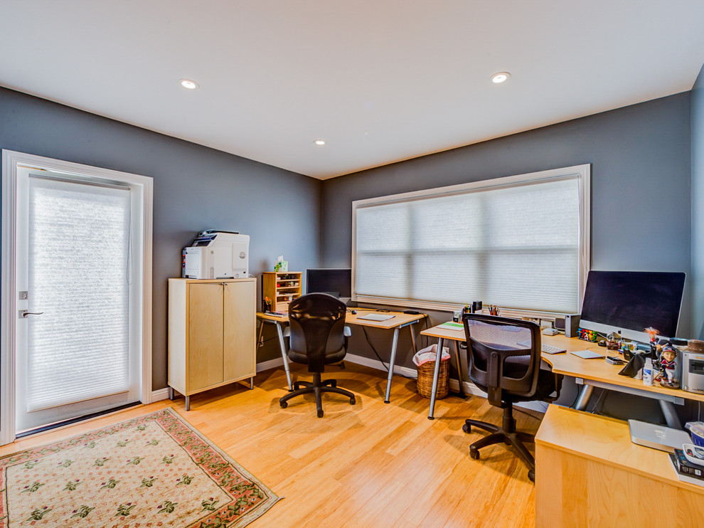 This is an example of a large beach style study room in San Francisco with blue walls, light hardwood floors and a freestanding desk.
