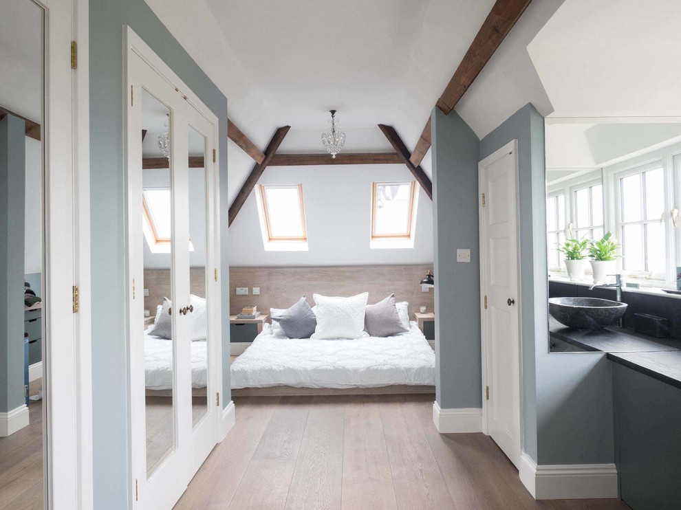 Photo of a mid-sized country guest bedroom in Gloucestershire with light hardwood floors and blue walls.