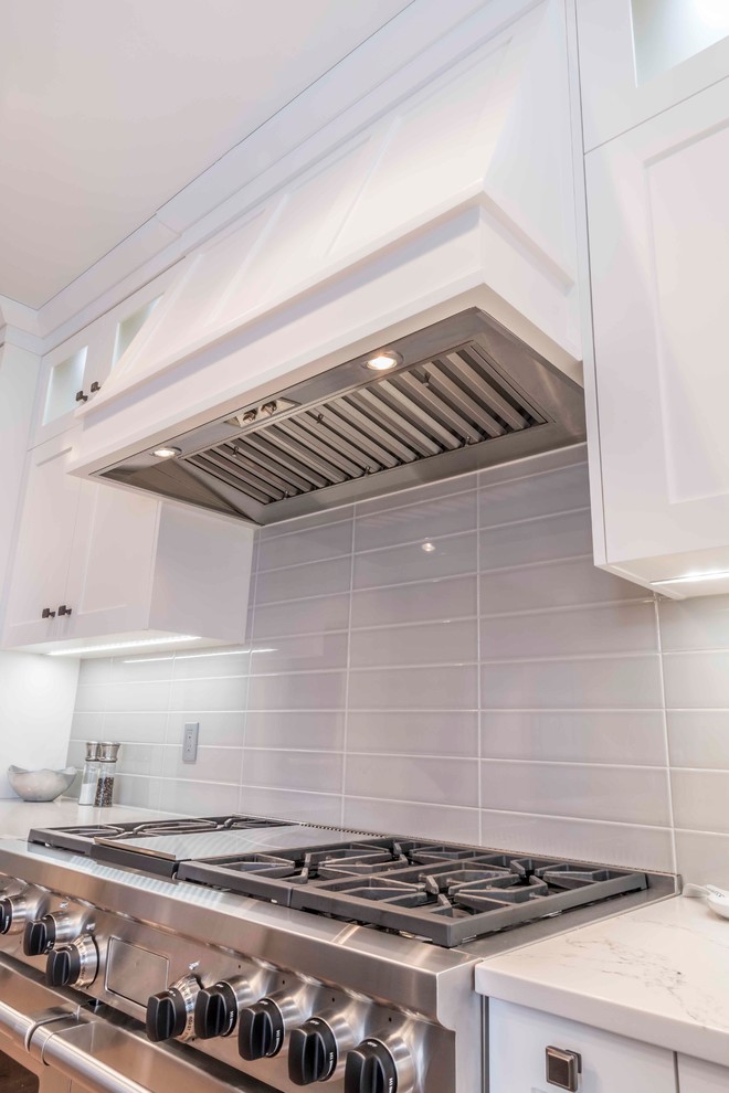 Kitchen - mid-sized transitional u-shaped medium tone wood floor and brown floor kitchen idea in Calgary with an undermount sink, flat-panel cabinets, white cabinets, marble countertops, gray backsplash, ceramic backsplash, paneled appliances and an island