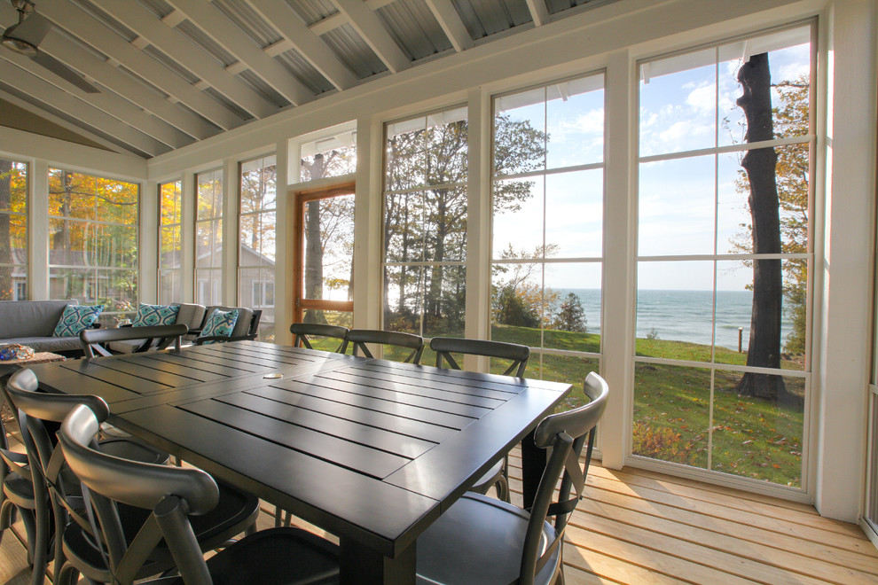 Small beach style screened-in back porch idea in Grand Rapids with decking and a roof extension