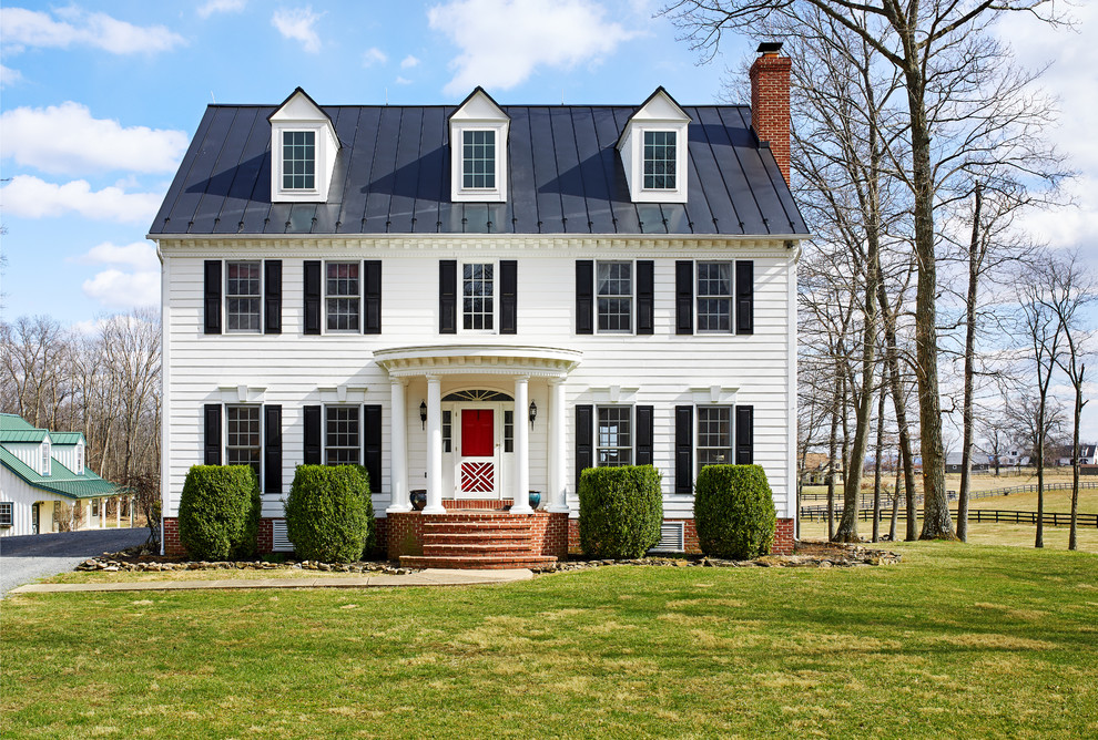 This is an example of a traditional three-storey white house exterior in DC Metro with a metal roof and a gable roof.