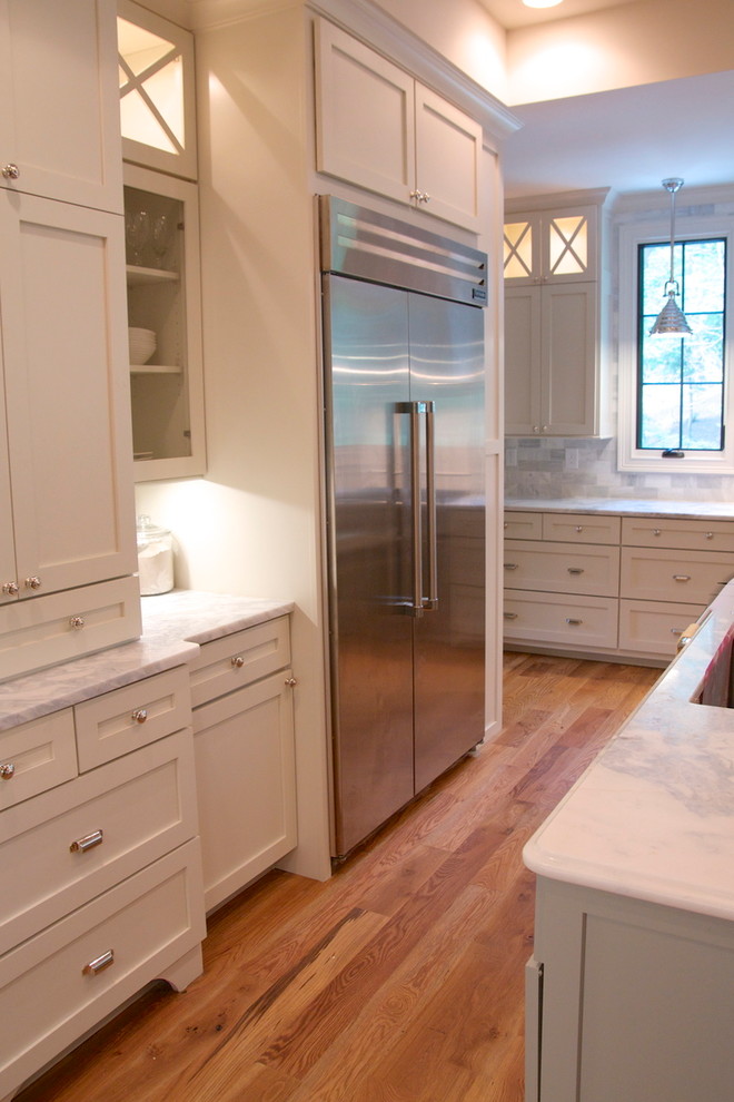 Huge transitional l-shaped light wood floor enclosed kitchen photo in Birmingham with a single-bowl sink, shaker cabinets, white cabinets, quartzite countertops, green backsplash, stone tile backsplash, stainless steel appliances, white walls and an island