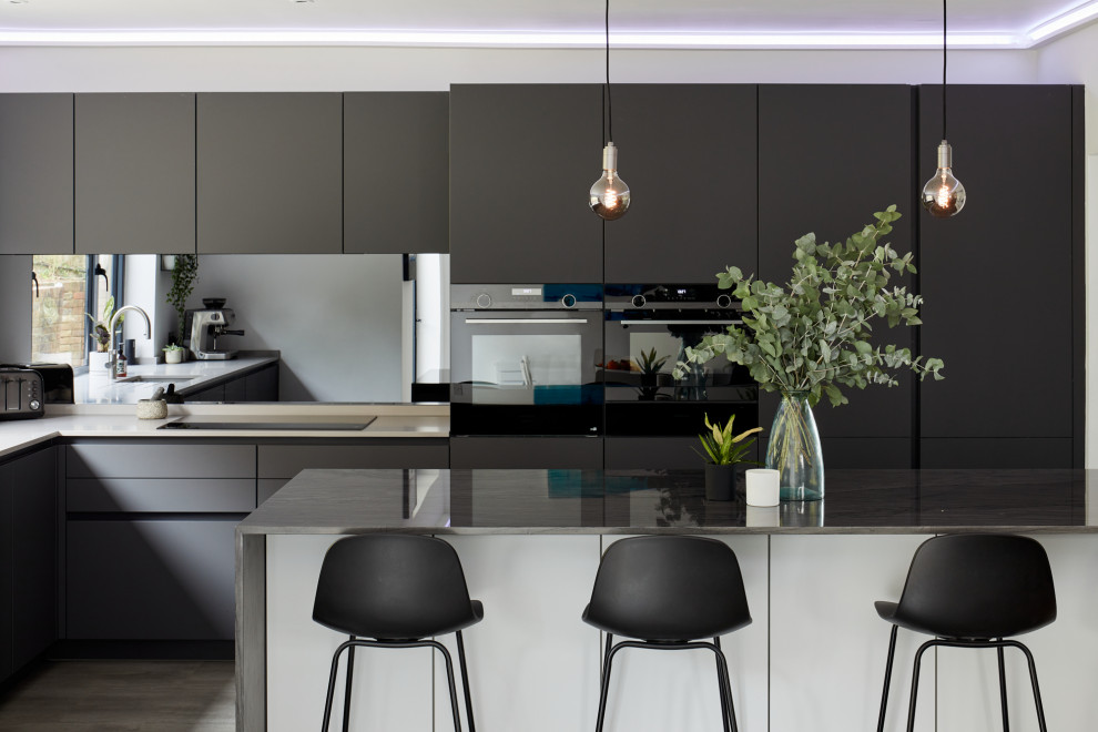 Photo of a mid-sized contemporary l-shaped eat-in kitchen in London with an undermount sink, flat-panel cabinets, grey cabinets, glass sheet splashback, stainless steel appliances and with island.