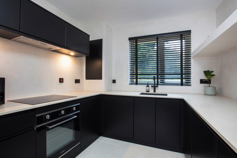 Inspiration for a medium sized contemporary u-shaped enclosed kitchen in London with an integrated sink, flat-panel cabinets, black cabinets, composite countertops, integrated appliances, porcelain flooring, beige floors and beige worktops.