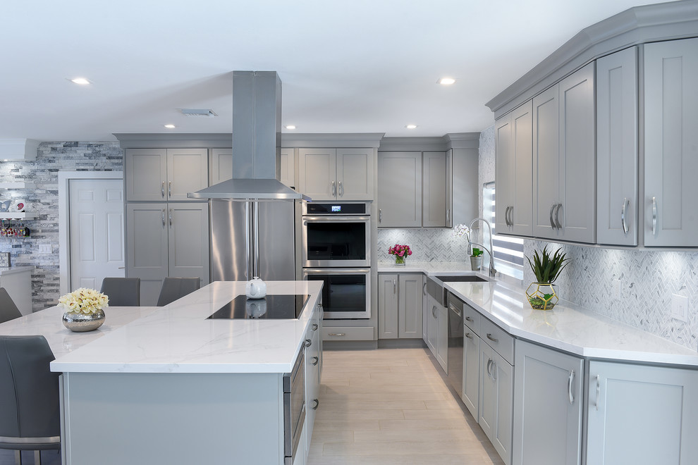 Example of a large transitional l-shaped porcelain tile and gray floor open concept kitchen design in Miami with a farmhouse sink, shaker cabinets, gray cabinets, quartz countertops, gray backsplash, marble backsplash, stainless steel appliances and two islands