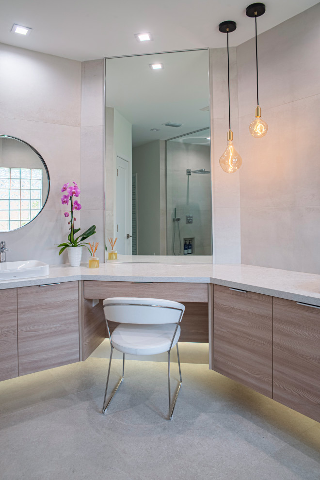 This is an example of a large modern ensuite bathroom in Miami with flat-panel cabinets, light wood cabinets, a freestanding bath, a shower/bath combination, a one-piece toilet, beige tiles, porcelain tiles, beige walls, porcelain flooring, a built-in sink, engineered stone worktops, beige floors, an open shower, beige worktops, an enclosed toilet, double sinks and a floating vanity unit.