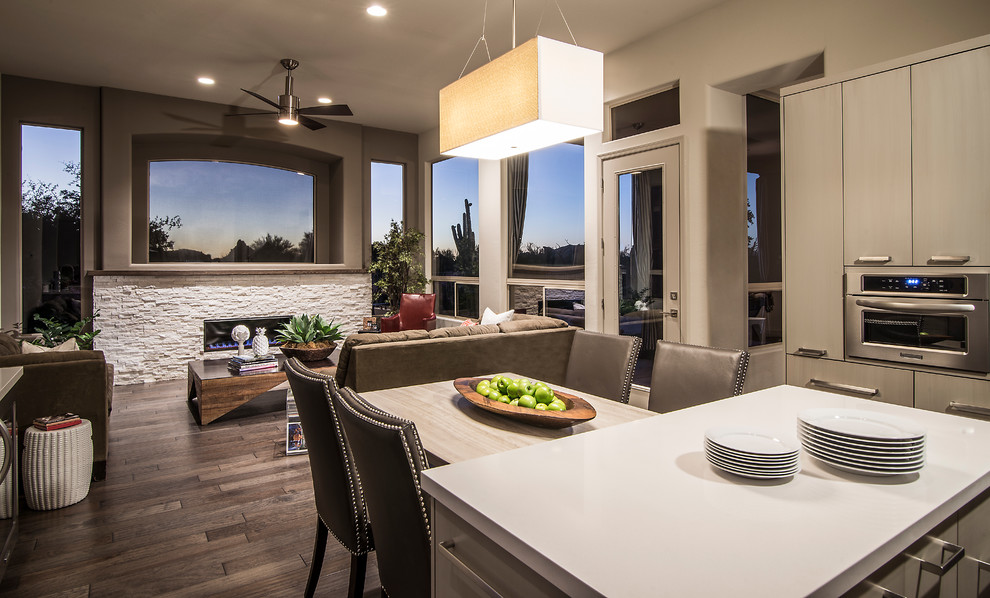 This is an example of a large contemporary u-shaped kitchen in Phoenix with a farmhouse sink, flat-panel cabinets, beige cabinets, solid surface benchtops, white splashback, mosaic tile splashback, stainless steel appliances, dark hardwood floors, with island, brown floor and white benchtop.