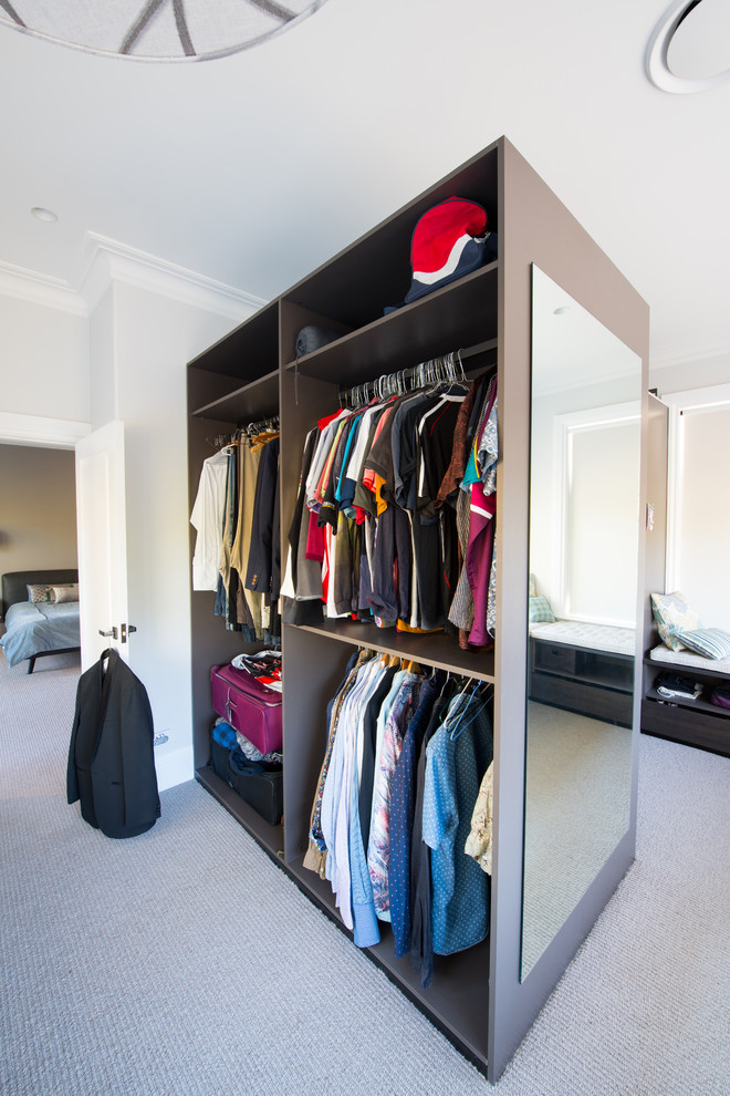 Large contemporary gender-neutral walk-in wardrobe in Sunshine Coast with open cabinets, dark wood cabinets, carpet and beige floor.