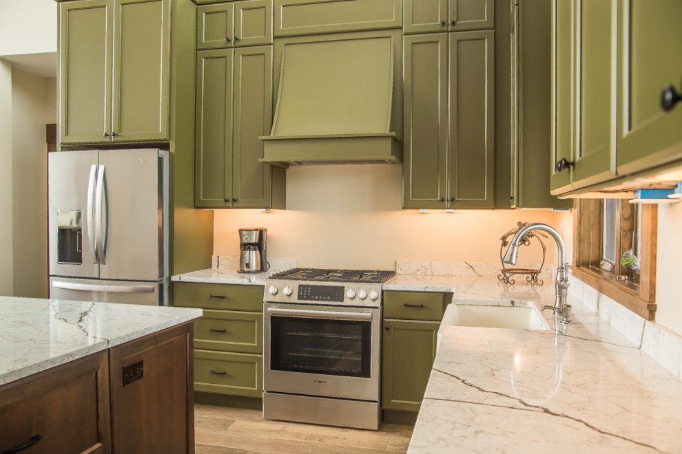 デトロイトにあるお手頃価格の中くらいなトラディショナルスタイルのおしゃれなキッチン (エプロンフロントシンク、落し込みパネル扉のキャビネット、緑のキャビネット、クオーツストーンカウンター、白いキッチンパネル、クオーツストーンのキッチンパネル、シルバーの調理設備、無垢フローリング、茶色い床、白いキッチンカウンター、表し梁) の写真