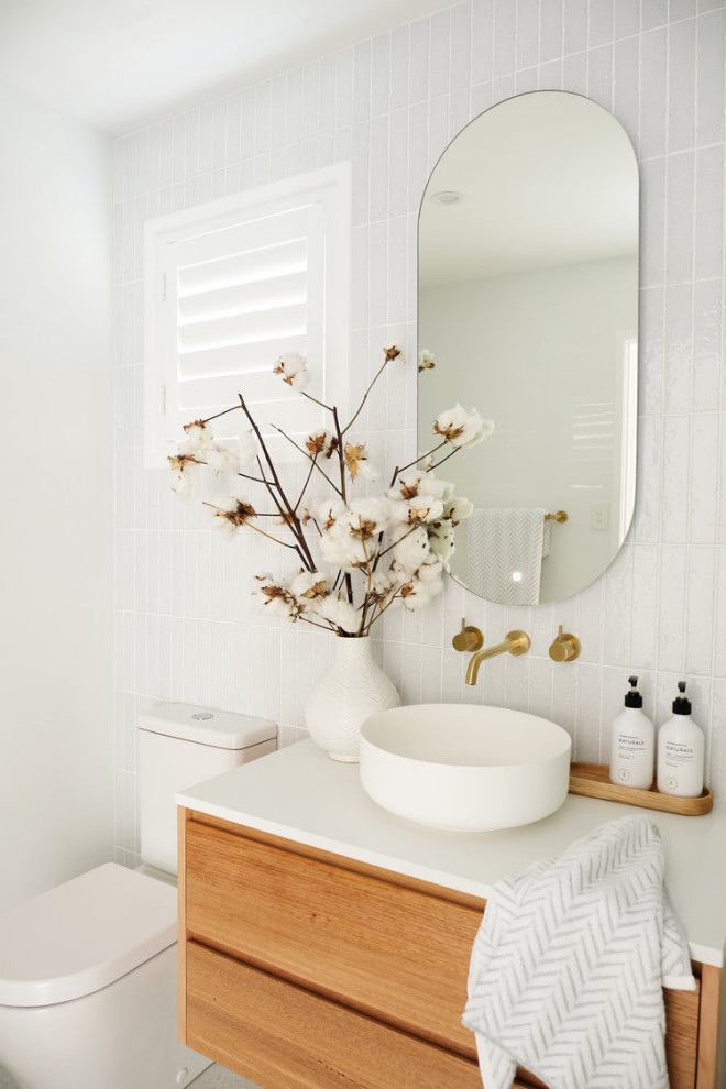 Small midcentury master bathroom in Los Angeles with medium wood cabinets, white tile, porcelain tile, laminate benchtops, white benchtops, flat-panel cabinets, a corner shower, a one-piece toilet, white walls, a drop-in sink, a hinged shower door, slate floors and beige floor.