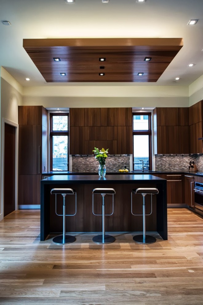 Photo of a large contemporary l-shaped open plan kitchen in DC Metro with flat-panel cabinets, dark wood cabinets, brown splashback, mosaic tile splashback, quartz benchtops, stainless steel appliances and light hardwood floors.