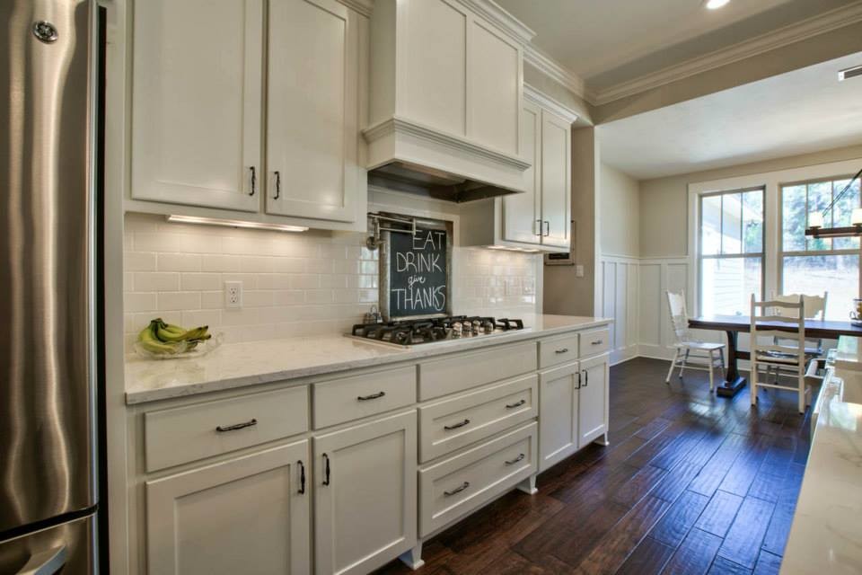 Inspiration for a large beach style l-shaped open plan kitchen in Atlanta with a farmhouse sink, shaker cabinets, white cabinets, marble benchtops, white splashback, subway tile splashback, stainless steel appliances, medium hardwood floors and with island.