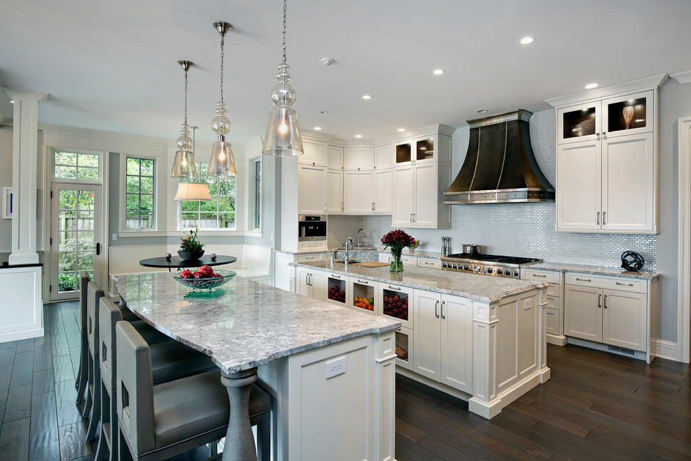 Example of a transitional medium tone wood floor open concept kitchen design in Chicago with recessed-panel cabinets, granite countertops, white backsplash, stainless steel appliances and two islands