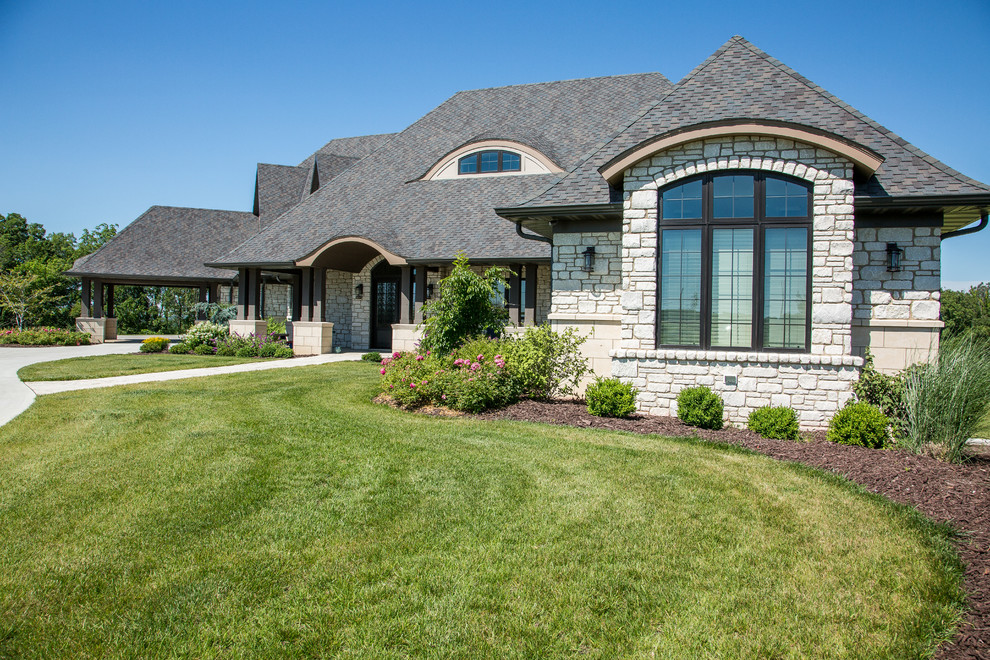Large traditional two-storey white house exterior in Other with stone veneer and a hip roof.