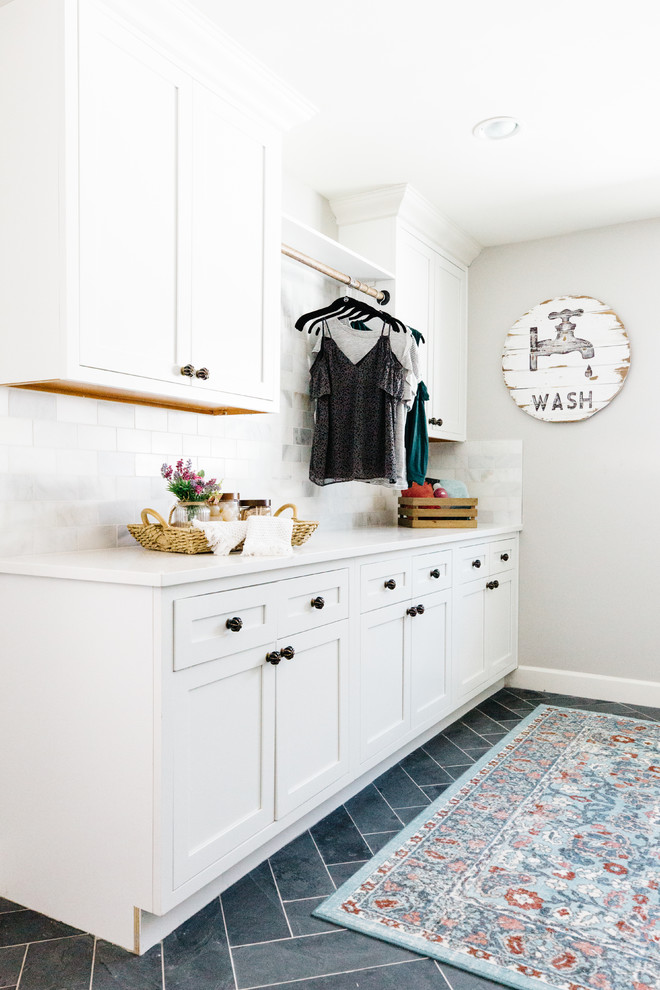 Photo of an expansive country galley dedicated laundry room in Phoenix with an utility sink, recessed-panel cabinets, white cabinets, quartz benchtops, grey walls, slate floors, a side-by-side washer and dryer and black floor.