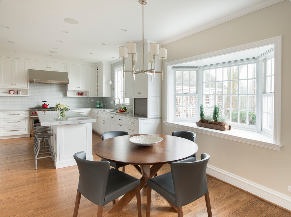 Mid-sized transitional l-shaped dark wood floor eat-in kitchen photo in Chicago with an undermount sink, white cabinets, quartzite countertops, white backsplash, glass tile backsplash, stainless steel appliances, an island and recessed-panel cabinets