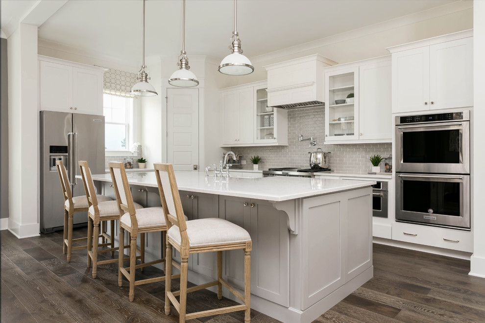 Inspiration for a large transitional l-shaped dark wood floor and brown floor open concept kitchen remodel in Charleston with a farmhouse sink, shaker cabinets, quartz countertops, gray backsplash, mosaic tile backsplash, stainless steel appliances, an island and white countertops