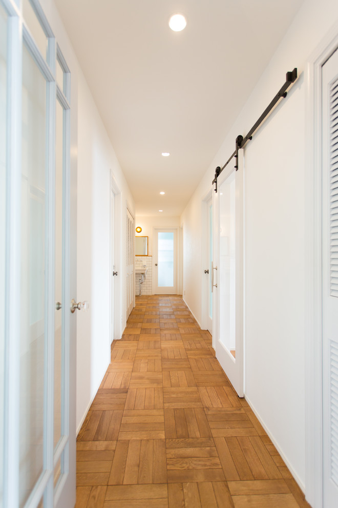 Design ideas for a mid-sized scandinavian hallway in Other with white walls, medium hardwood floors and brown floor.