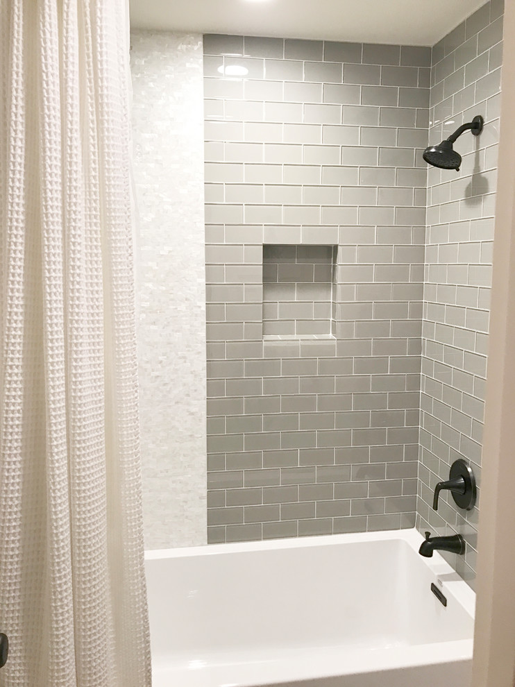 This is an example of a small country kids bathroom with raised-panel cabinets, white cabinets, an alcove shower, a two-piece toilet, gray tile, glass tile, grey walls, porcelain floors, an undermount sink, quartzite benchtops, grey floor, a shower curtain and grey benchtops.