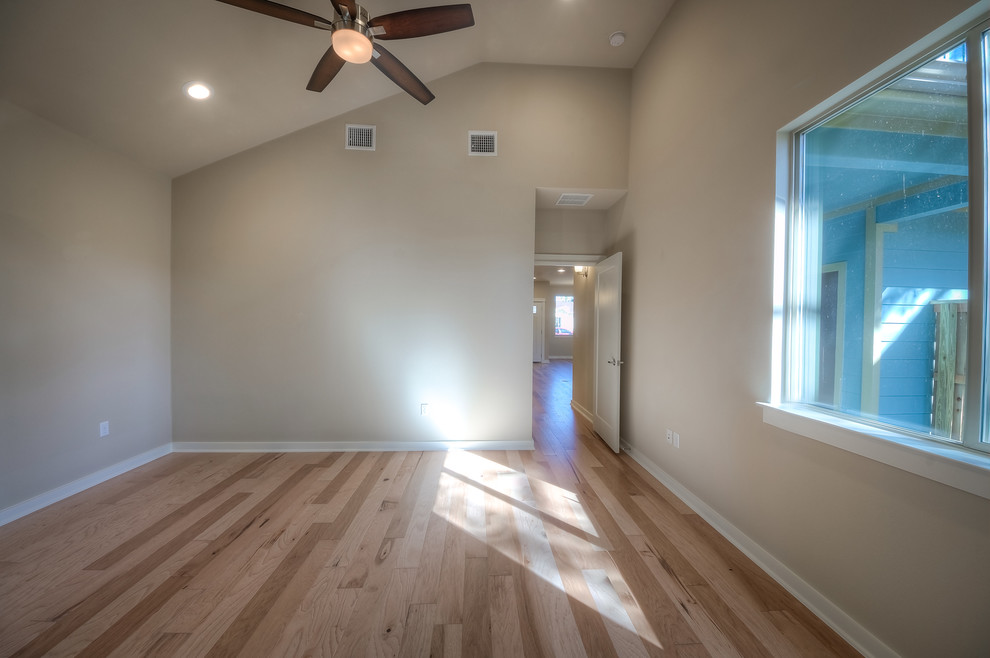 Mid-sized contemporary master bedroom in Austin with beige walls and light hardwood floors.