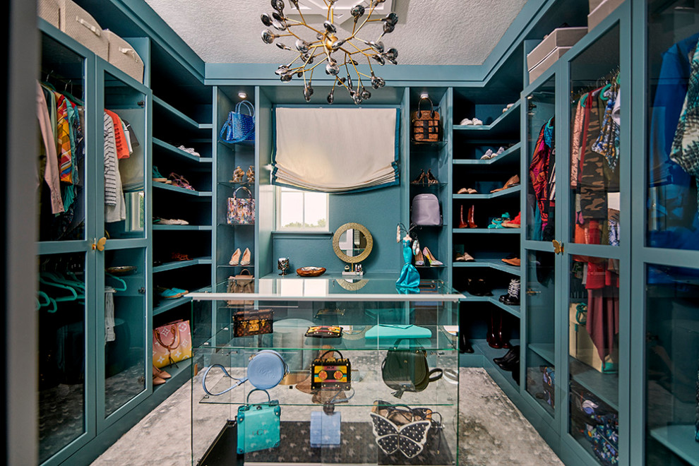Large eclectic gender neutral walk-in wardrobe in Orlando with glass-front cabinets, blue cabinets, carpet and multi-coloured floors.