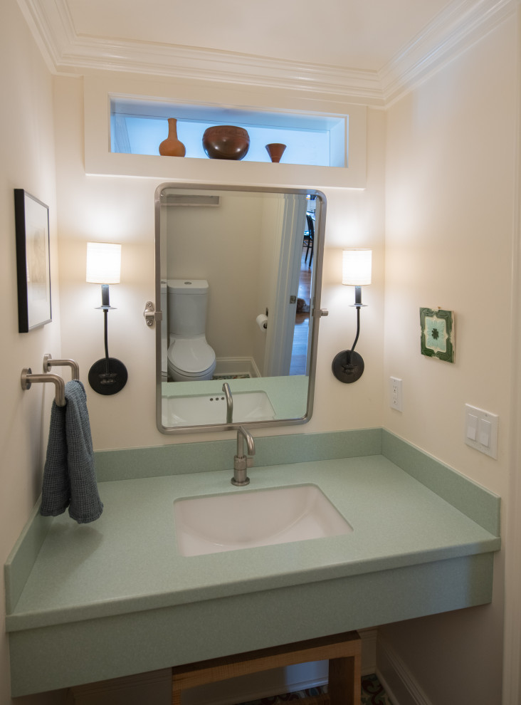 Foto på ett litet eklektiskt grön badrum, med en toalettstol med separat cisternkåpa, cementgolv, ett undermonterad handfat och bänkskiva i akrylsten