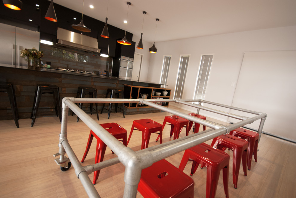 This is an example of a large industrial kitchen/dining combo in Brisbane with white walls and light hardwood floors.