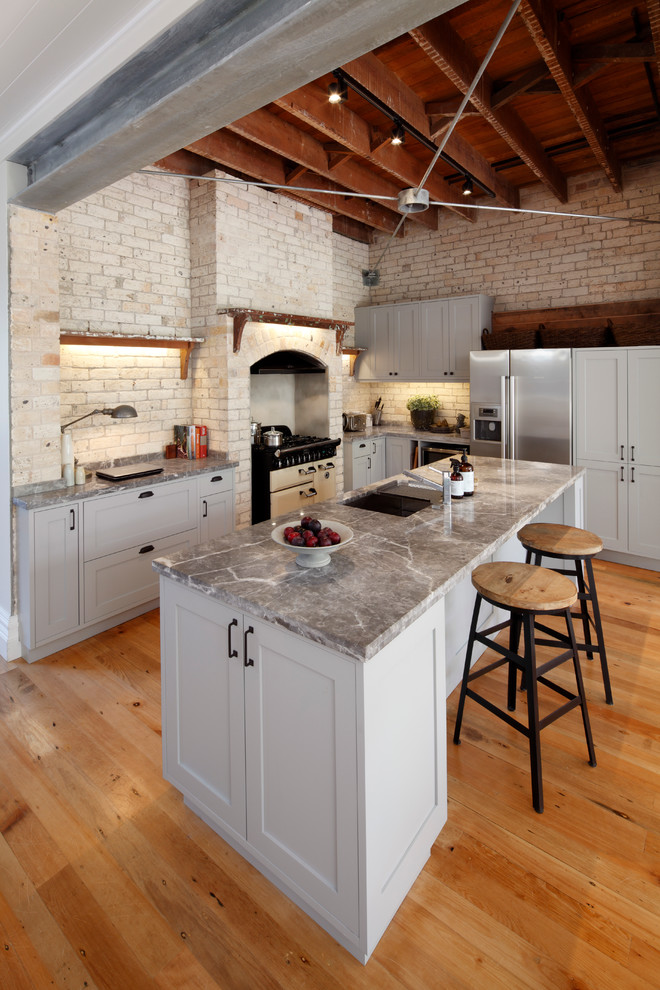 Industrial l-shaped eat-in kitchen in Sydney with an undermount sink, grey cabinets, marble benchtops, beige splashback, stainless steel appliances, medium hardwood floors and with island.