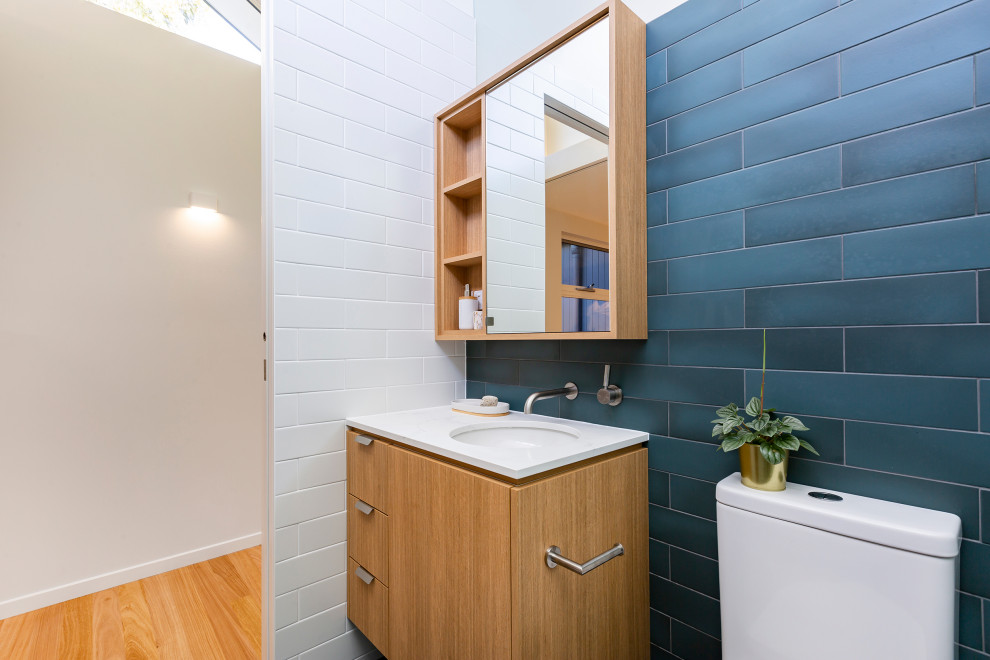 Exempel på ett litet modernt en-suite badrum, med bruna skåp, en toalettstol med hel cisternkåpa, cementkakel, vita väggar, cementgolv, bänkskiva i kvarts, blått golv och släta luckor