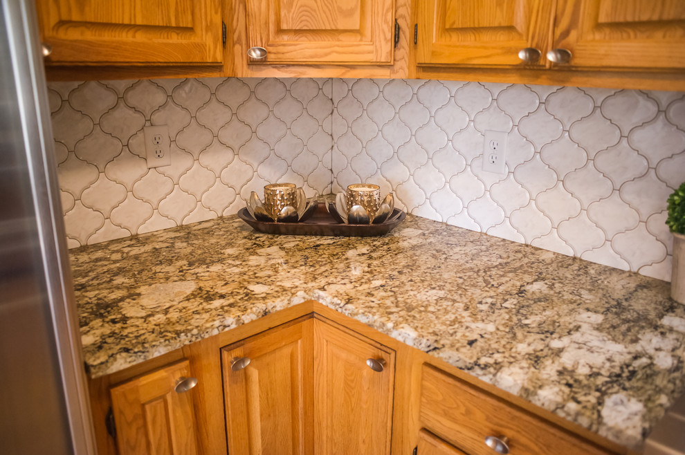 Eat-in kitchen - small modern u-shaped medium tone wood floor eat-in kitchen idea with raised-panel cabinets, medium tone wood cabinets, quartzite countertops, white backsplash, porcelain backsplash, stainless steel appliances and an island
