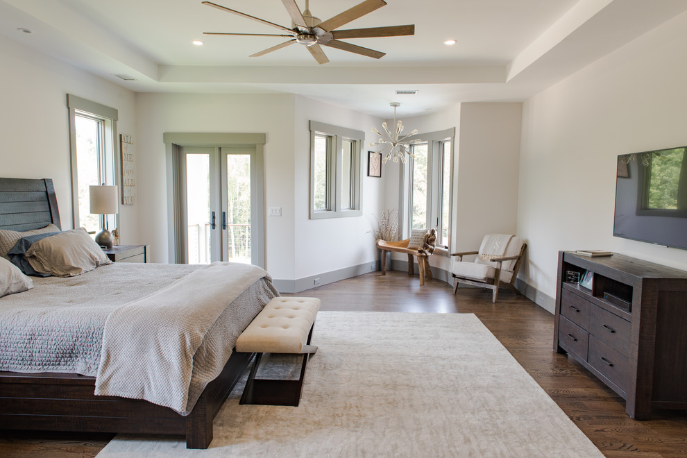 Photo of a large country master bedroom in Charleston with beige walls, dark hardwood floors, a two-sided fireplace, a wood fireplace surround and brown floor.
