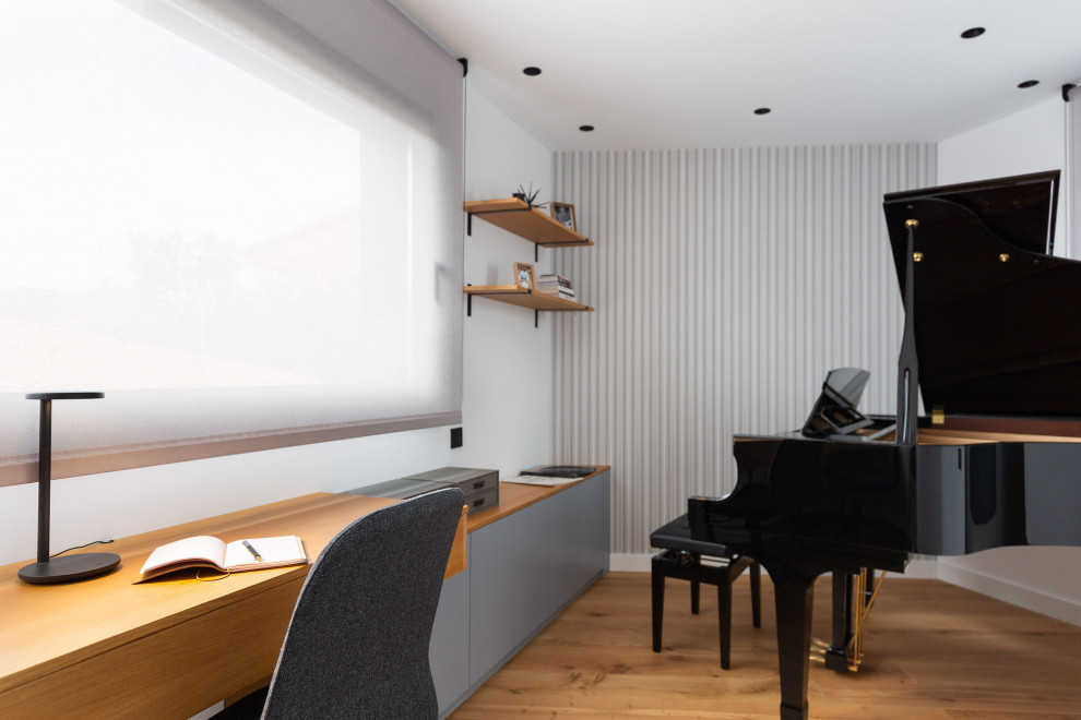 Modern inredning av ett mellanstort hemmastudio, med mellanmörkt trägolv, ett inbyggt skrivbord och brunt golv
