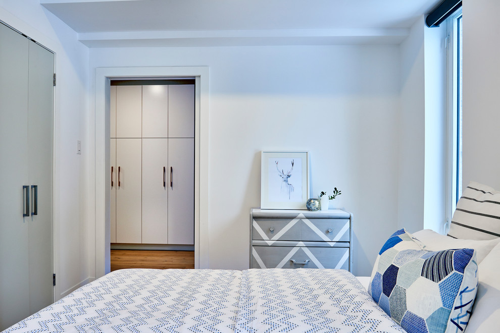 Scandinavian guest bedroom in Toronto with white walls and light hardwood floors.