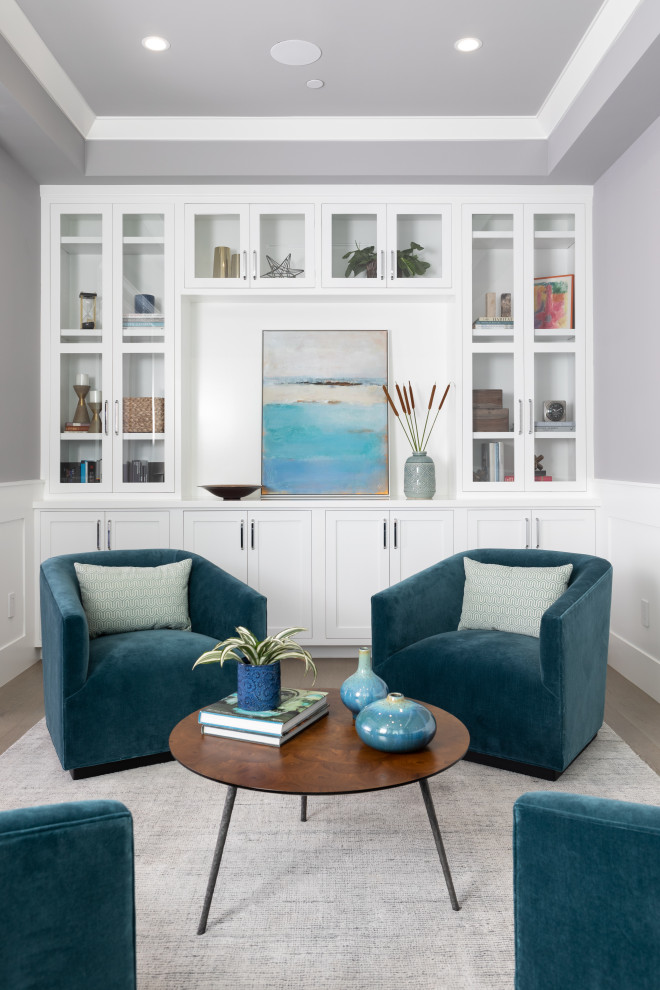 Inspiration for a mid-sized beach style living room in Los Angeles with light hardwood floors, no fireplace, a library, grey walls and no tv.