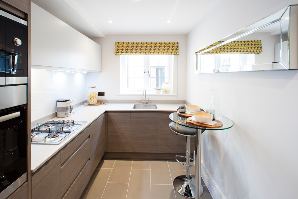 This is an example of a small contemporary l-shaped kitchen in Dorset with flat-panel cabinets and glass tile splashback.