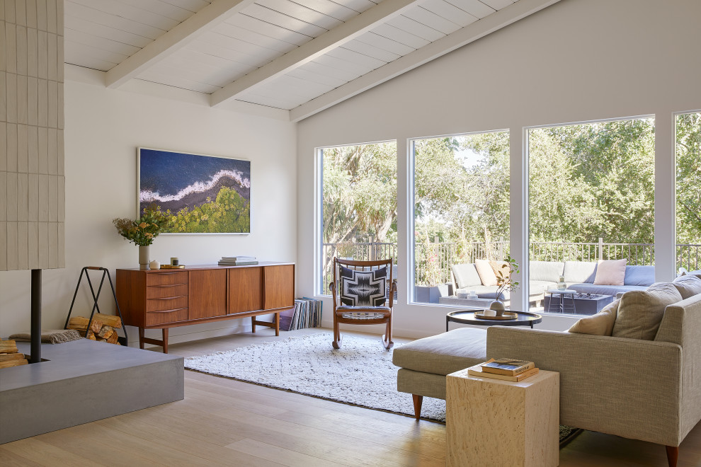 Photo of a mid-sized midcentury open concept living room in San Francisco with white walls, light hardwood floors, a corner fireplace, a brick fireplace surround, a wall-mounted tv, brown floor and exposed beam.