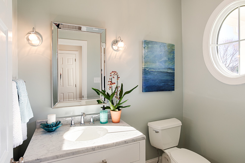 Inspiration for a mid-sized transitional powder room in Philadelphia with white cabinets, a two-piece toilet, grey walls, an undermount sink, marble benchtops and recessed-panel cabinets.