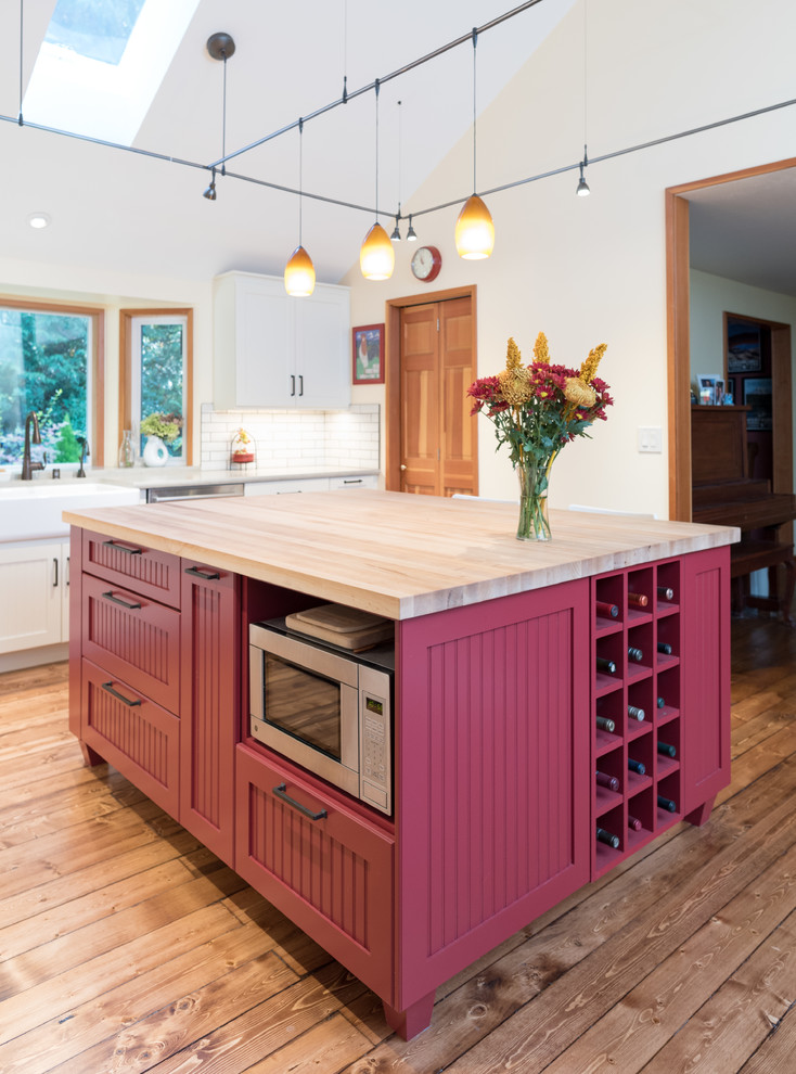 Inspiration for a mid-sized country l-shaped eat-in kitchen in Seattle with a farmhouse sink, recessed-panel cabinets, white cabinets, solid surface benchtops, white splashback, ceramic splashback, stainless steel appliances, with island, brown floor, dark hardwood floors, brown benchtop and vaulted.