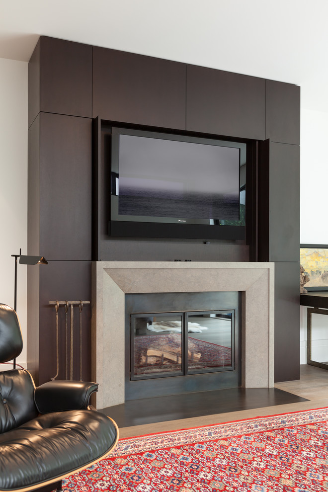 This is an example of a mid-sized modern enclosed living room in San Francisco with a standard fireplace, a concealed tv, brown floor, white walls, light hardwood floors and a tile fireplace surround.