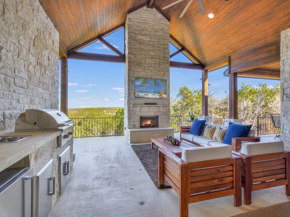 Photo of a large backyard verandah in Austin with with fireplace, concrete slab and a roof extension.