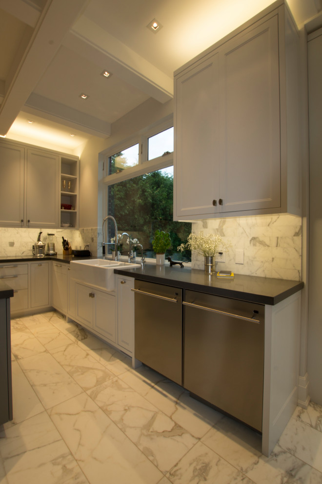 Inspiration for a large transitional l-shaped marble floor, white floor and coffered ceiling enclosed kitchen remodel in Toronto with a farmhouse sink, shaker cabinets, white cabinets, quartzite countertops, white backsplash, marble backsplash, stainless steel appliances, an island and gray countertops