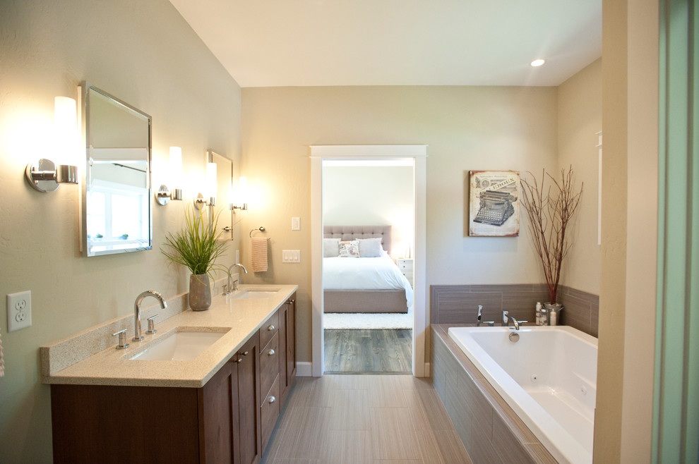 Example of a large transitional master gray tile and ceramic tile ceramic tile drop-in bathtub design with an undermount sink, shaker cabinets, quartz countertops, gray walls and dark wood cabinets