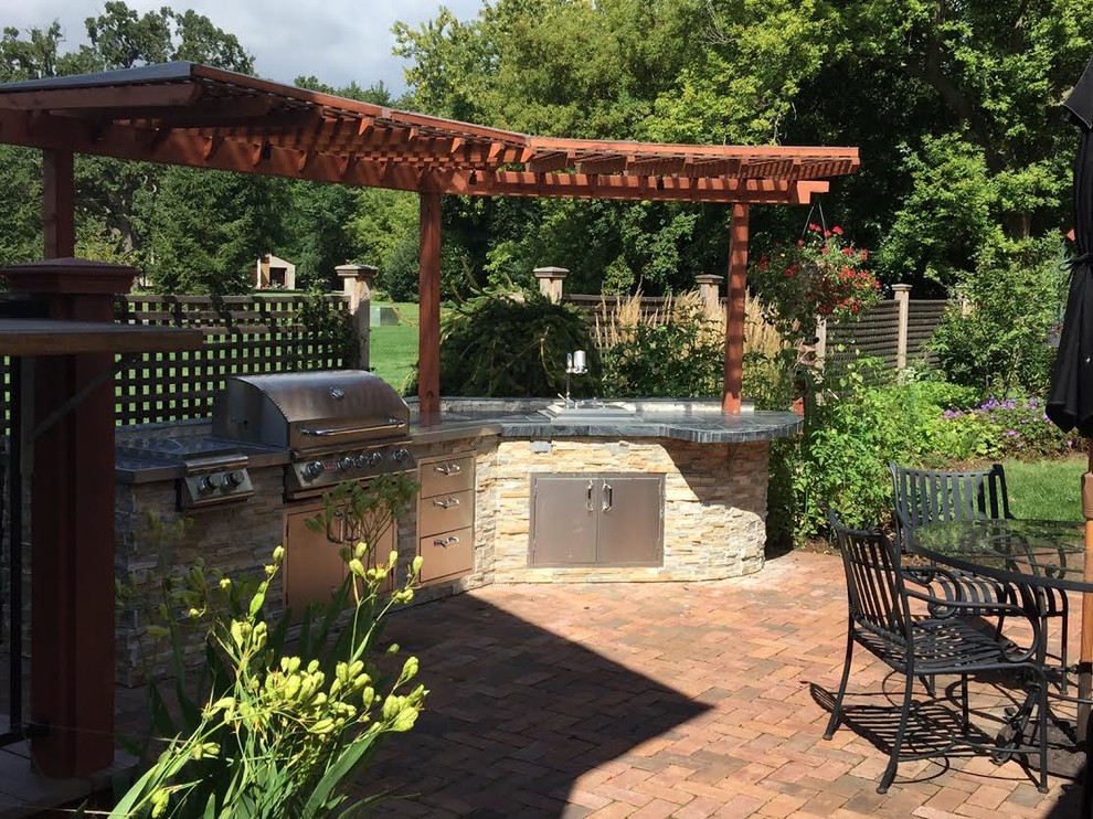 Mid-sized traditional backyard patio in Milwaukee with an outdoor kitchen, brick pavers and a pergola.