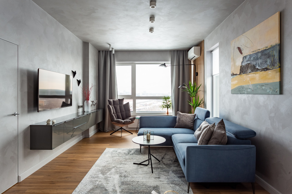 Idée de décoration pour un grand salon design avec un mur gris, sol en stratifié, un téléviseur fixé au mur et un sol beige.