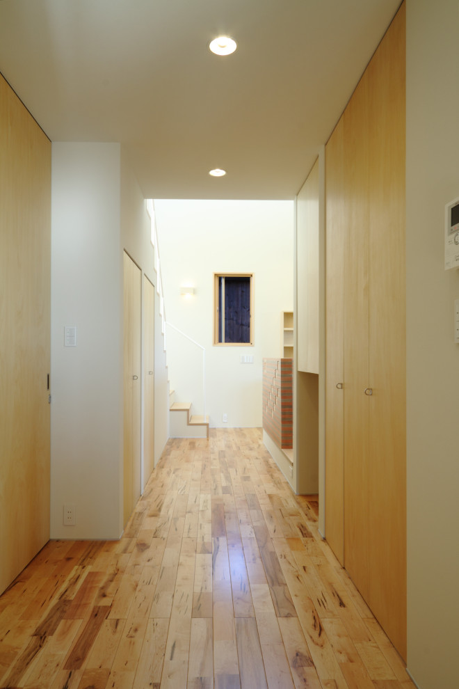Foto di un ingresso o corridoio moderno di medie dimensioni con pareti bianche, pavimento in legno massello medio, pavimento marrone, soffitto in carta da parati e carta da parati